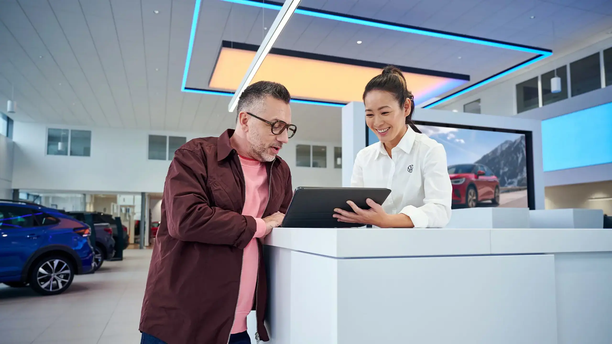 En kvindelig VW medarbejder viser en kunde noget på en ipad i en forhandler